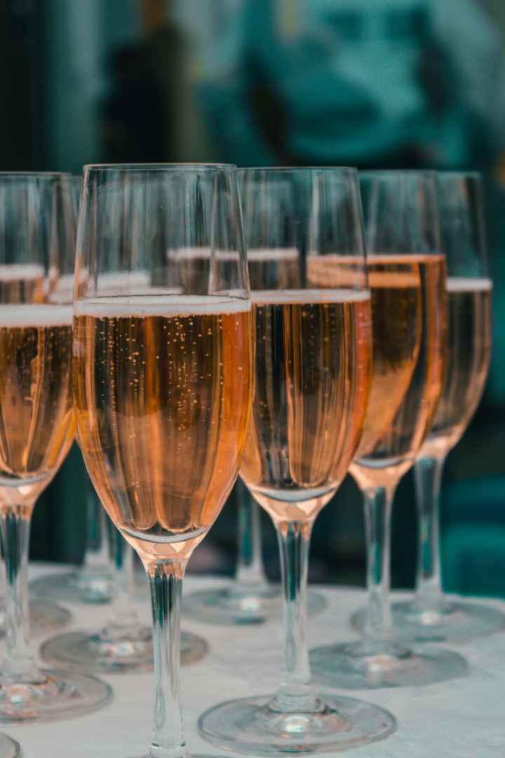 Row of champagne flutes filled with sparkling pink or rose-colored wine
