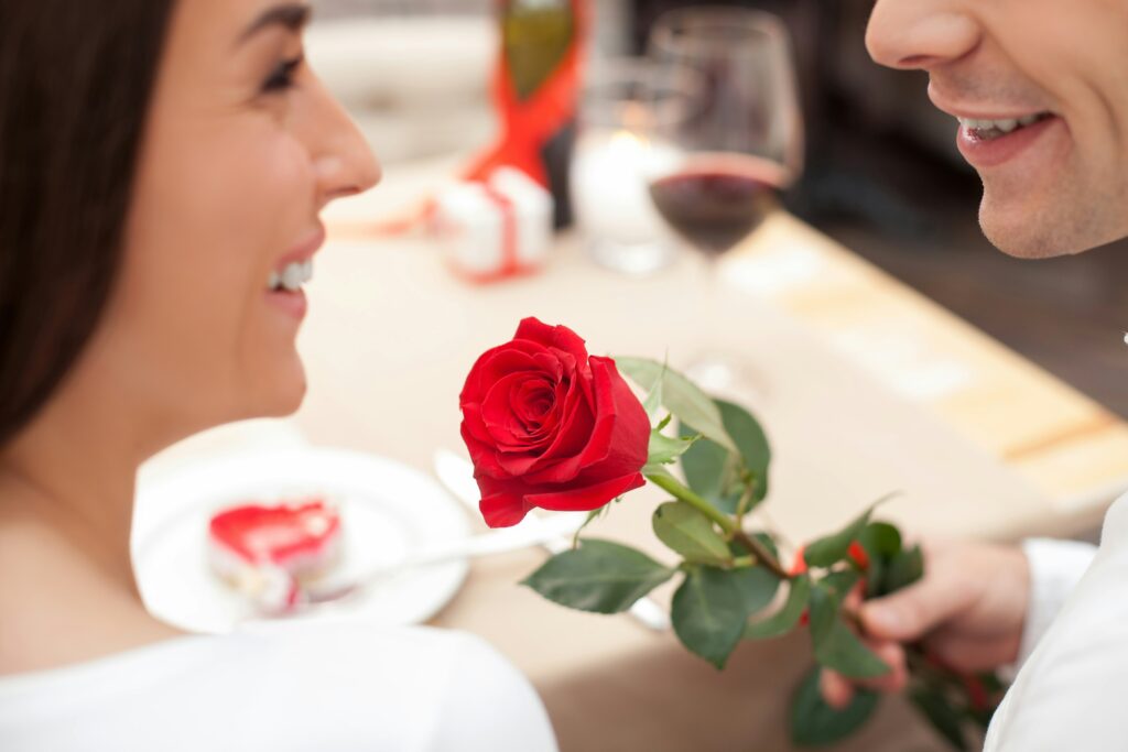 couple enjoying a personalized wine experience at home with wine gifts, a red rose, and heart-shaped treats, representing the ultimate gift for any wine lover.