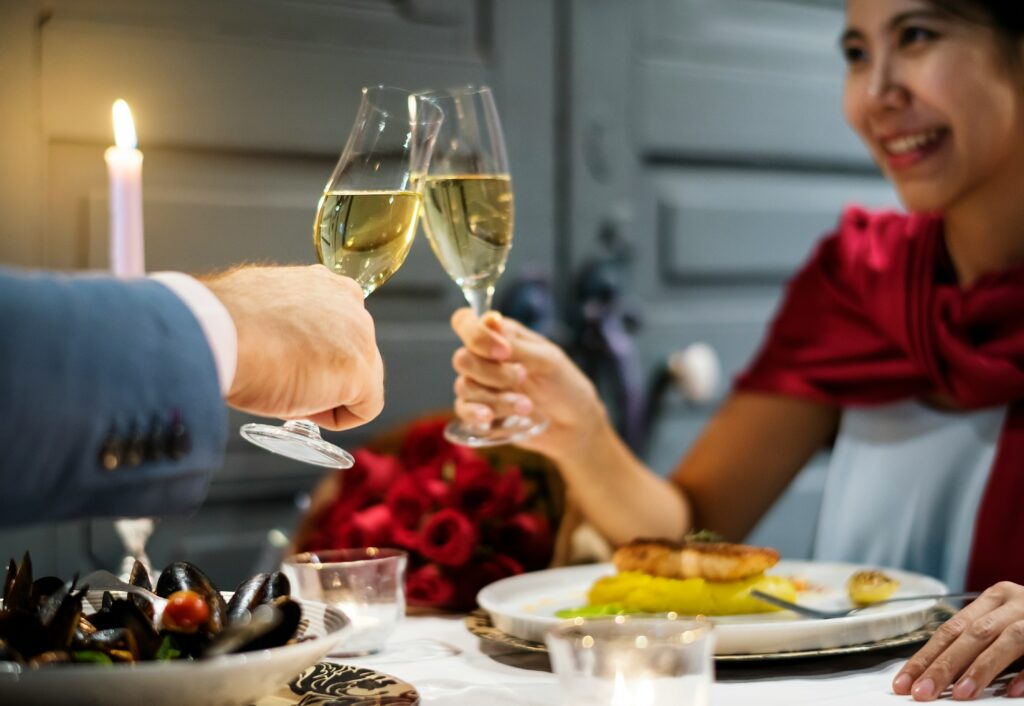 A smiling couple toasting with glasses of sparkling wine during a romantic Valentine’s Day dinner, illustrating how to avoid common Valentine’s Day wine myths by choosing quality over prestige.
