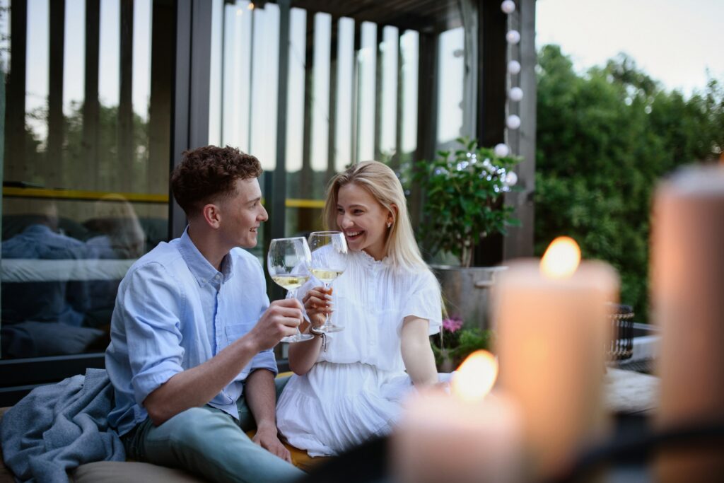 A close-up of a couple clinking glasses of white wine over a candlelit table, avoiding the wines people regret buying for Valentines day.